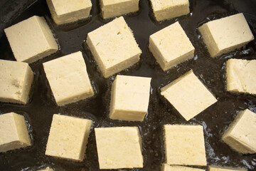 Pieces of tofu are fried in a frying pan.Vegan food ingredient in Asian cuisine, Plant based diet. food concept.