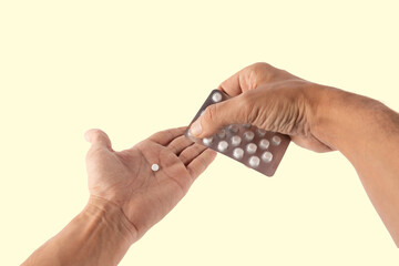 Male hands getting a pill from a medicine blister isolated on yellow background