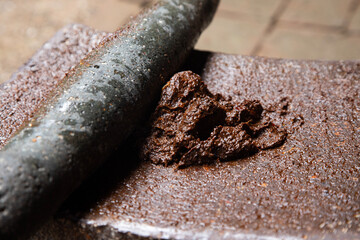 Woman from an indigenous community in Oaxaca preparing traditional Black mole with a metate, a tool for grinding ingredients in Mexico.
