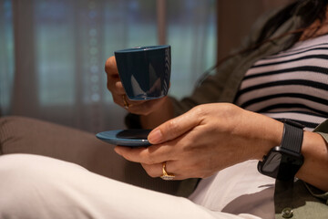 Unidentified woman holding cup of coffee during relax in living room