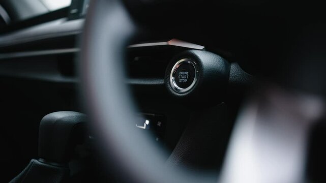 Close-up of a car start button being pressed by a woman. Concept of modern technology, convenience, and innovation in cars.