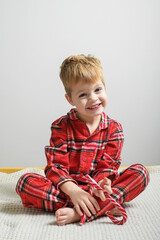 Thoughtful Little Boy in Red Plaid Shirt Relaxing on Cozy Surface.