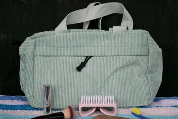 Hellgrüne Kulturtasche (Kosmetiktasche) aus hellgrünem Cord  für Reisen. Nagelbürste, Nagelfeile, Seife, Lippenstift, Zahnbürste auf gestreiftem Frotteehandtuch.