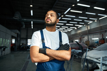 Handsome mechanic stands proudly in a well lit garage, showcasing his skills and dedication.