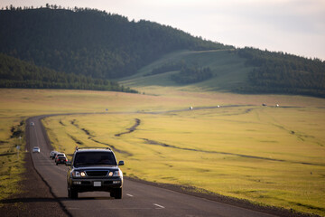Japanese black SUV moving by a road in summer in Mongolia