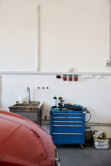Red car in modern well lit garage next to sink and tools.