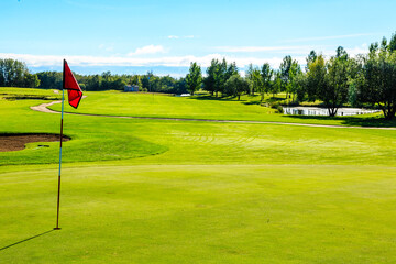 Obraz premium A golf course with a red flag on the green grass