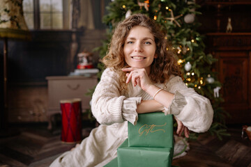 Woman enjoying the festive atmosphere near a beautifully decorated Christmas tree with gifts during the holiday season