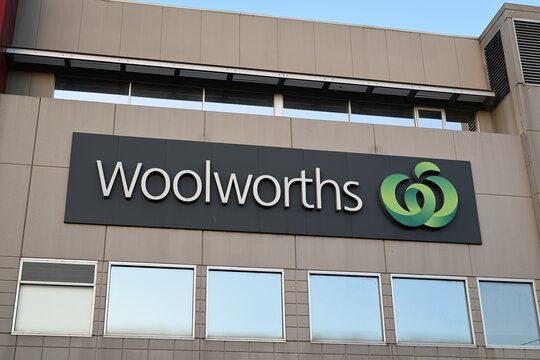 Large elevated Woolworths supermarket sign on the side of a building, featuring the grocery company's green logo