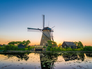 Fototapeta premium Beautiful sunset over traditional windmill and serene lake in a rural landscape