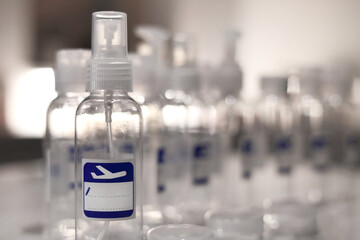 Small, transparent, plastic liquid bottles for plane traveling. Blank label with blue plane icon.