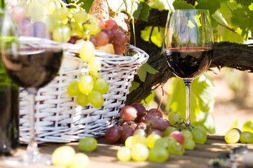 Still life with glass of red wine grapes and picnic basket on table