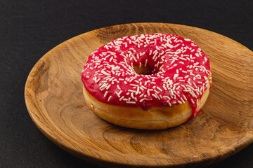 fresh delicious donut with red glaze on a wooden plate,