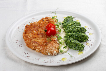 Chicken schnitzel served with sauce, accompanied by broccoli and cheese fritters.
