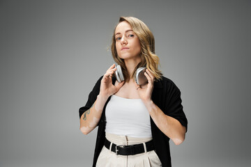 Young woman with vitiligo showcases her style while holding headphones in a modern studio.