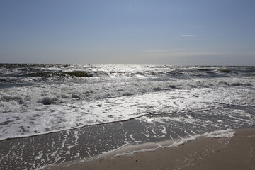 Sunlit Ocean Waves and Sandy Shoreline: A stunning seascape showcasing sparkling ocean waves under a bright sunny sky, with foam washing onto the sandy beach, evoking tranquility and summer vibes.