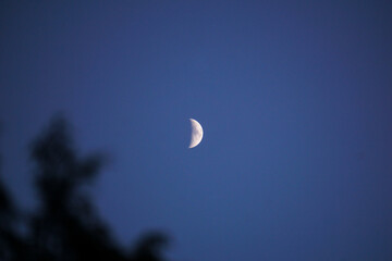 A bright moon in a blue sky without stars