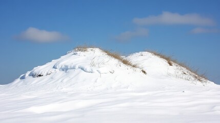Snow-covered dune hills under clear blue sky with wispy clouds