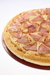 Close-up of a freshly baked ham and cheese pizza.