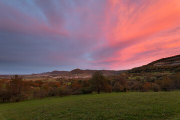 Obraz premium Blick auf die Burgfestung Hohenneuffen mit den drei Kaiserbergen am Horizont. Schwäbischen Alb im Herbst und einem gigantischen Sonnenuntergang.