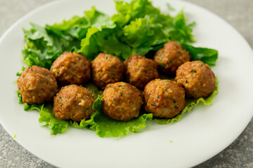 Of meatballs with lettuce on it. Of meatballs with meat on it. A plate of meatballs lies on a white plate with greens. A plate of meatballs lies on a white plate with meat lifestyle and greens.