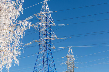 High-voltage wires and poles are covered with frost on a frosty winter day.
