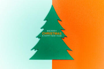 Closeup view of a wooden Christmas tree ornament with the text of Merry Christmas and Happy New Year on a colored background