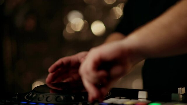 Dj mixing music on a controller showcases colorful lights against a blurred background, creating an energetic atmosphere typical of nightclubs and parties