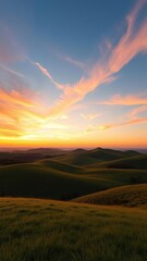 Obraz premium The sky is painted with hues of orange and pink as wispy clouds drift lazily across a vast expanse of green hills at sunset, natural scenery, sunset