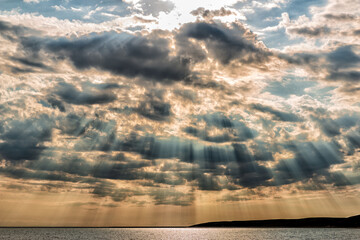 Beautiful daily landscape with the rays of the sun due to the clouds above the water surface of the...
