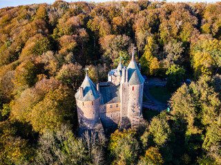 Aerial view of a medieval fairy tale castle surrounded by beautiful autumn foliage (Castell Coch, Wales)