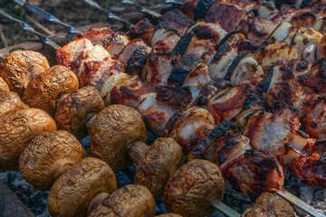 Shashlik of champignon mushrooms and chicken meat is fried on the grill. Close-up.