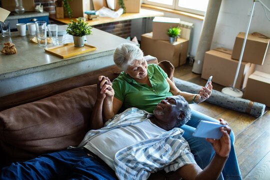 Senior couple relaxing on couch in new home with moving boxes around them