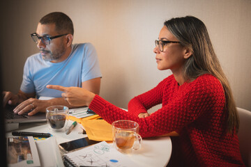 Two people are sitting at a table with a laptop and a cup of tea, couple organizing credit documents .New home concept.