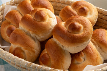 Basket with fresh homemade white buns of bread in a special shape close up
