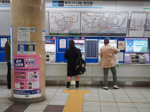 TOKYO, JAPAN - December 7, 2024: People using ticket machines at a Tokyo Metro subway station.
