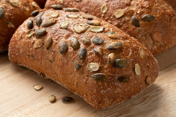 Fresh homemade baked pumpkin seed bun on a cutting board close up