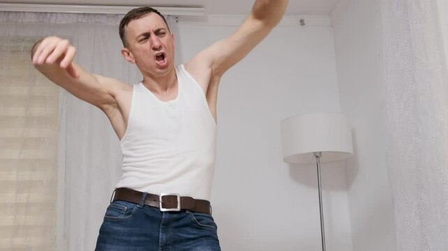 Man in casual clothing dances awkwardly in slow motion, showcasing a humorous and clumsy expression of joy