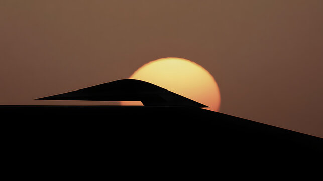 A stealth bomber silhouetted against the glow of a rising sun.