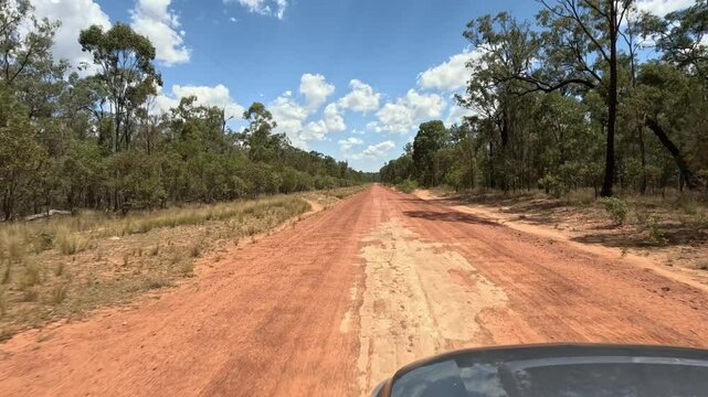 4K video, driving along red dirt outback country road, Queensland Australia, empty open landscape terrain , bushland trees blue sky