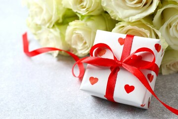 Gift box with bouquet of white roses on gray background