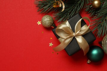 Top view of gift box tied with bow, Christmas decorations, confetti on color background 