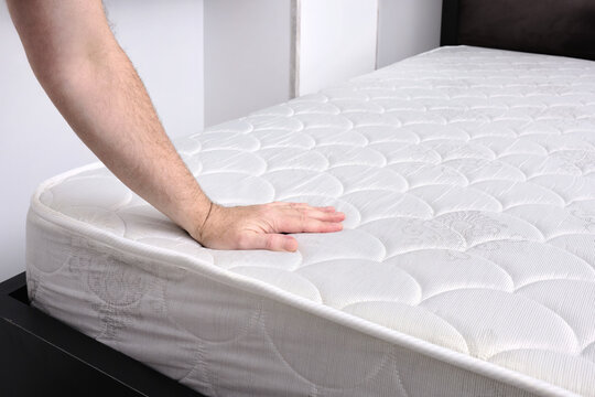 A adult man checks the quality of a new mattress in his bedroom.