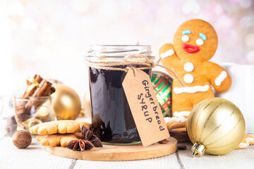 Homemade gingerbread syrup in jar, Christmas cookies and cake, drinks and cocktails ingredient with honey, sugar, spices, on kitchen table with gingerbread cookies and Christmas decorations 