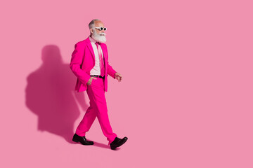 Full size photo of cool santa claus male macho walking dressed sunglass trendy pink suit isolated over pastel color background