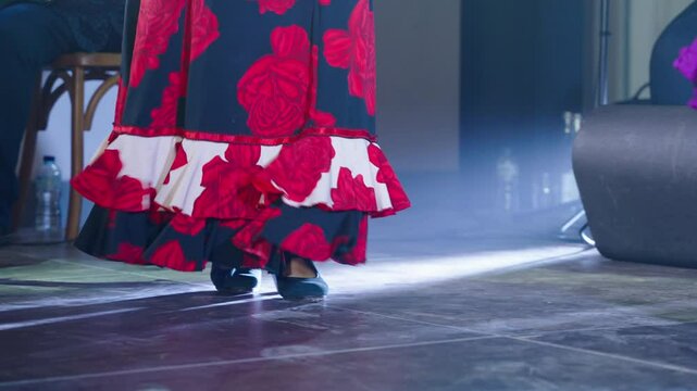 Women wearing colorful traje de flamenca dance on stage