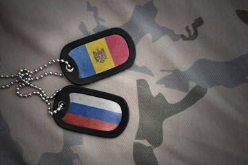 vintage army blank, dog tag with flag of moldova and russia on the khaki texture background....