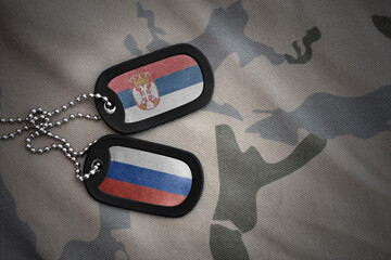 vintage army blank, dog tag with flag of serbia and russia on the khaki texture background....