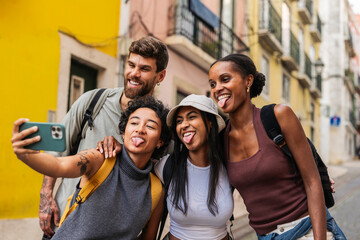 Obraz premium Tourists taking selfie sticking out tongues in lisbon, portugal