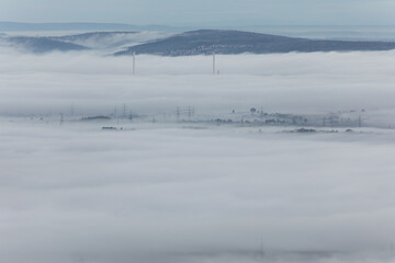 Stromleitung ragen aus dem Nebelmeer heraus. Altbacher Schornsteine im Nebel. 